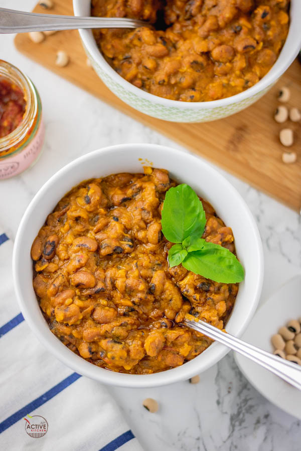 Nigerian stewed beans in a bowl (ewa riro) with a garnish of basil leaves.