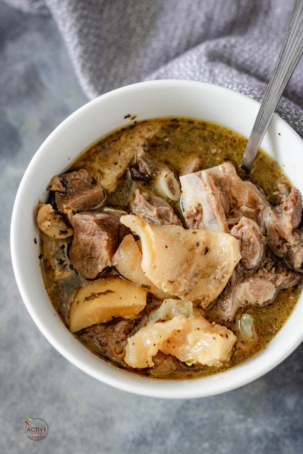 overhead shot of nigerian assorted meat pepper soup in a white bowl.