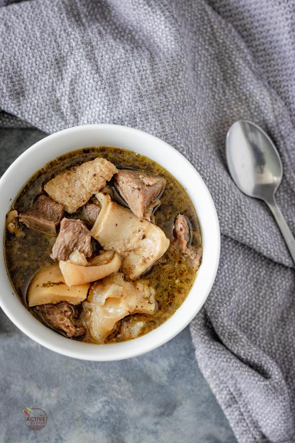 overhead shot of nigerian assorted meat pepper soup in a white bowl.