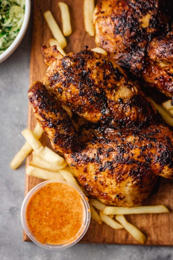 spactchcocked chicken piri piri and chips on a serving board.