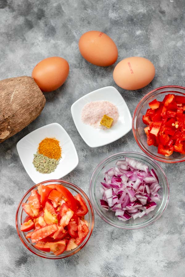 breakfast ingredients; yam, eggs, chopped tomatoes, chopped onions, chopped ata rodo, curry, salt, and thyme.