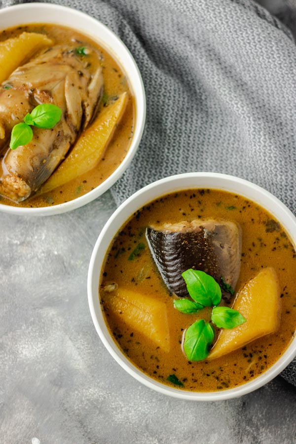 catfish pepper soup in two separate bowl placed on a coloured board with grey napkin thrown on the side of the bowls 