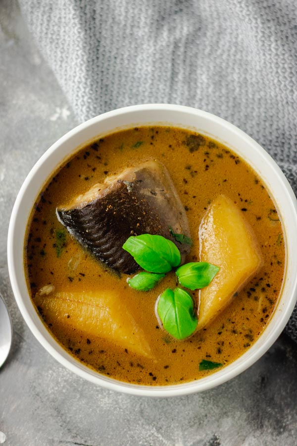 catfish pepper soup with plantain in a white bowl. 