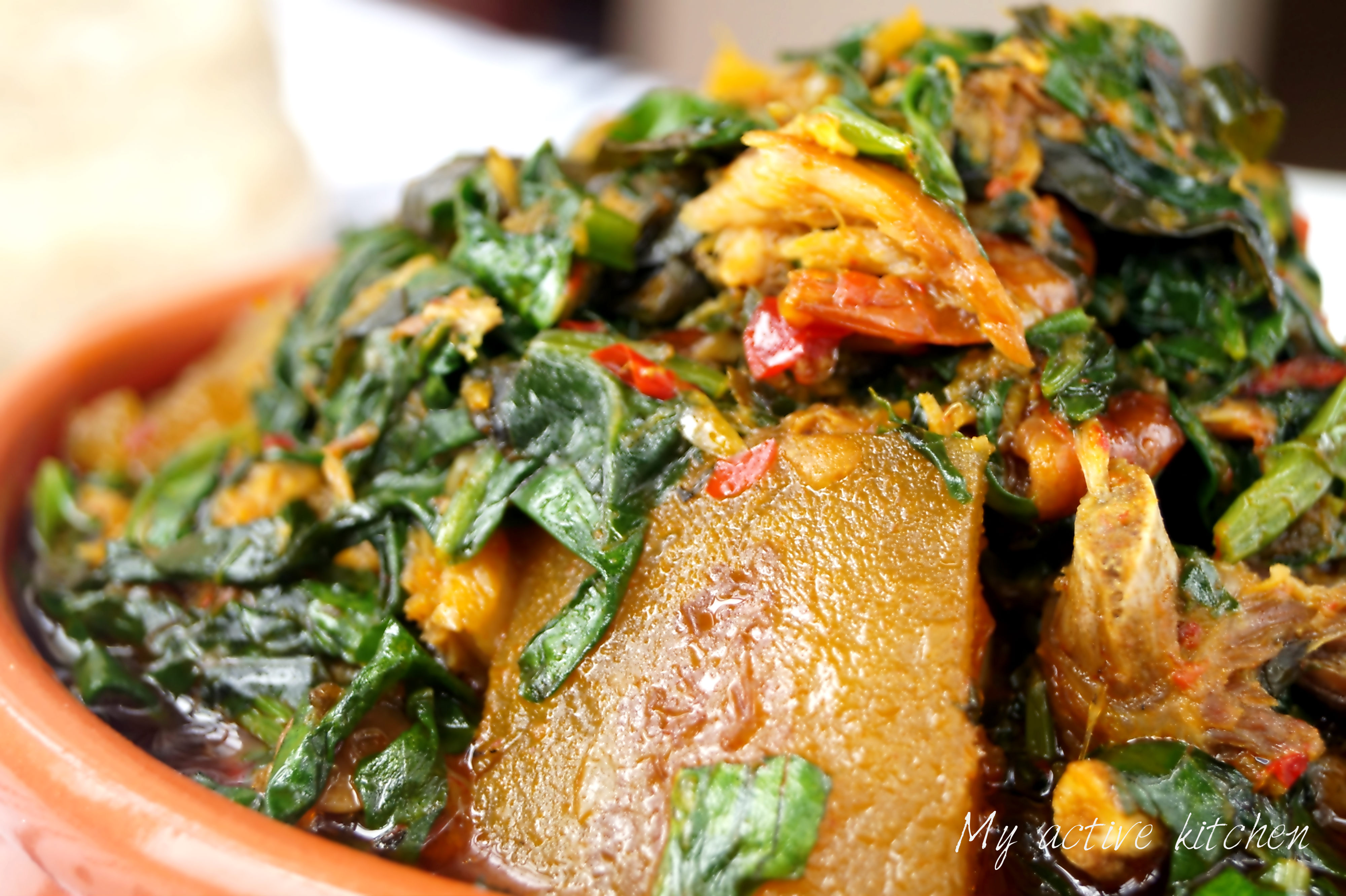 A close shot of efo riro (spinach stew) in a brown ceramic bowl