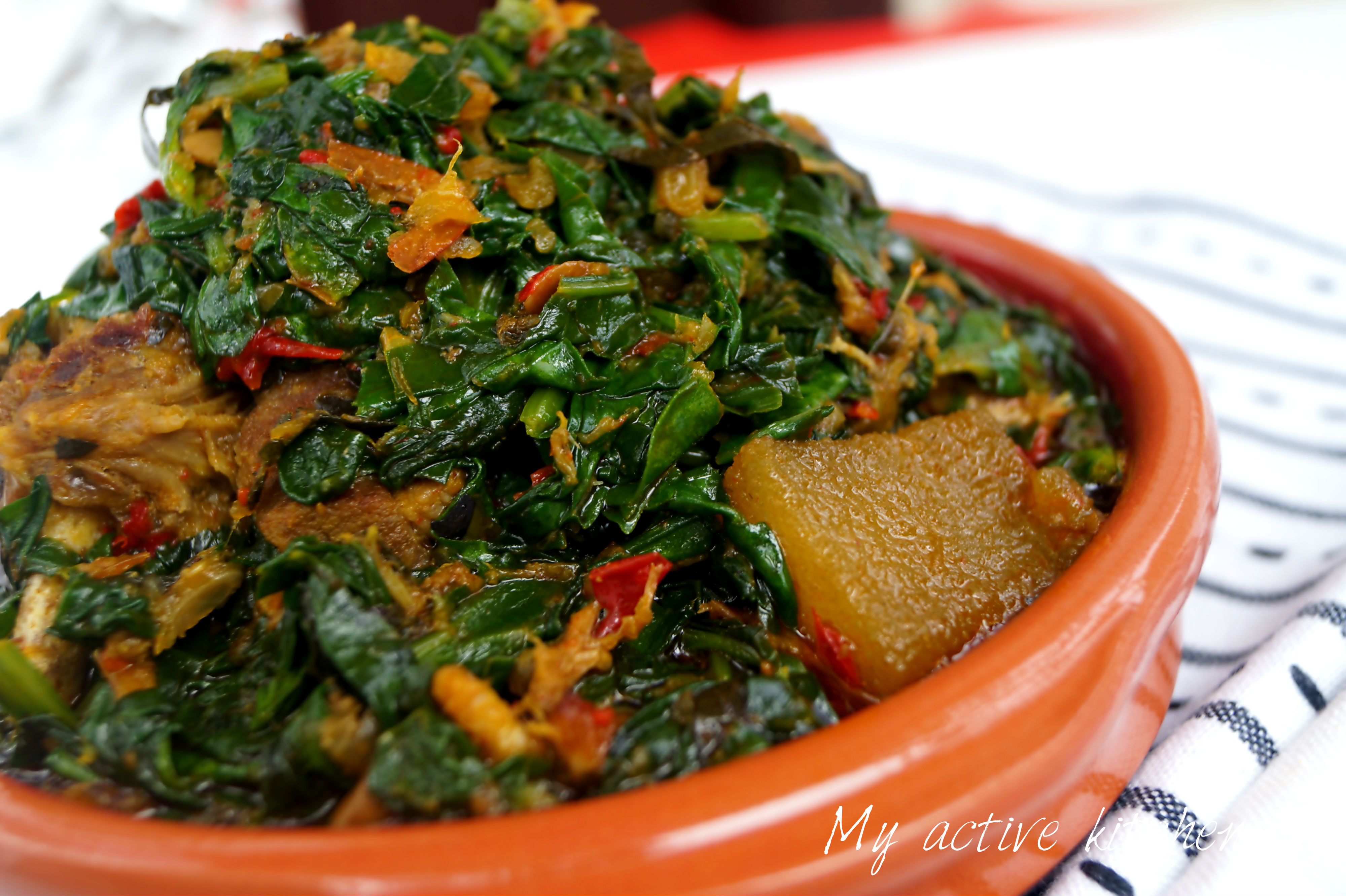 angled shot of efo riro in a brown ceramic bowl placed on a napkin