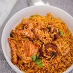 palm oil rice (local jollof rice) in a white bowl.