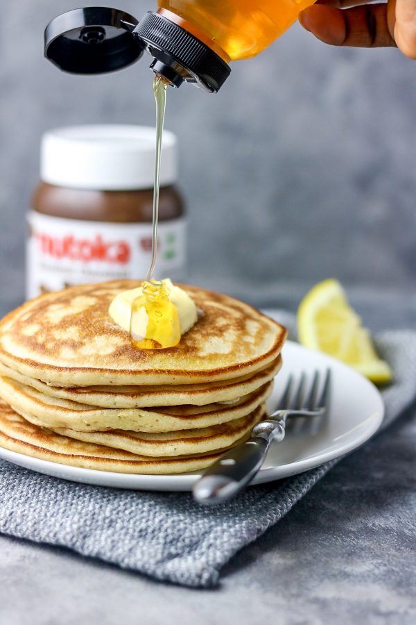 an action pour shot of honey over stack of pancakes