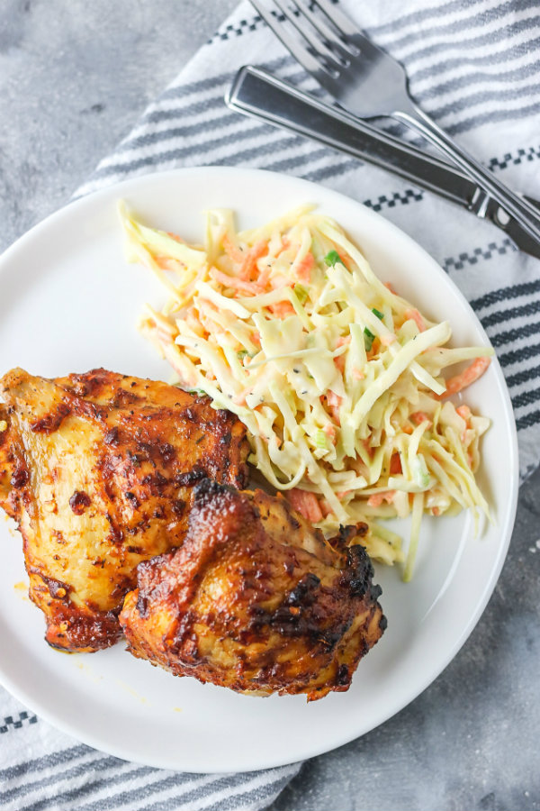 baked spicy chicken thigh on a plate with coleslaw