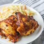 baked spicy chicken thigh on a plate with coleslaw