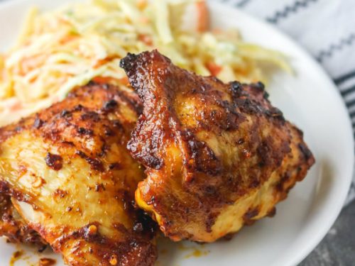 baked spicy chicken thigh on a plate with coleslaw