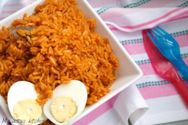 vegetarian nigerian jollof rice in a white bowl placed on a pink napkin
