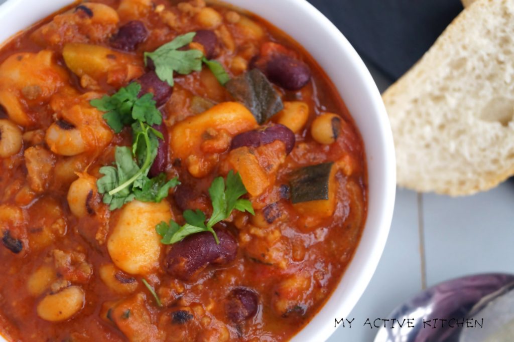 overhead shot of 3 bean chilli garnished with parsley and a side of crusty bread