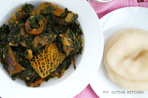 overhead shot of Edikang ikong in a white plate with a side of fufu