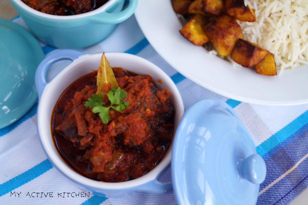 nigerian stew on a blue ramekin, garnished with parsley and dried bay leaf