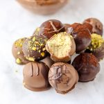 chocolate truffle on a white marble table with a bowl of chocolate on the side