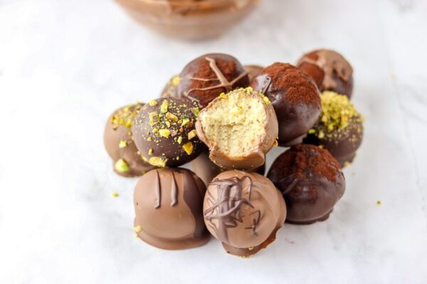 chocolate truffle on a white marble table with a bowl of chocolate on the side