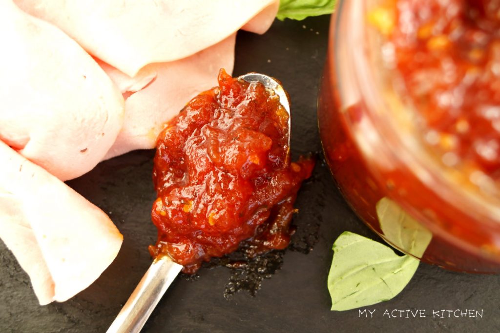 overhead shot of spicy tomato jam in a spoon jam. ham slices and thin sandwich bread.