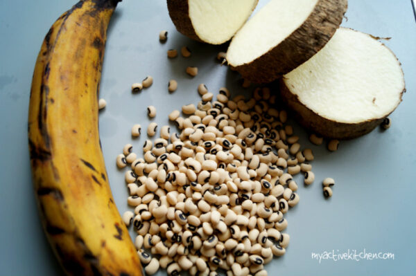 image of 1 ripe plantain, 3 slices of yam ans some black eyed beans on grey board