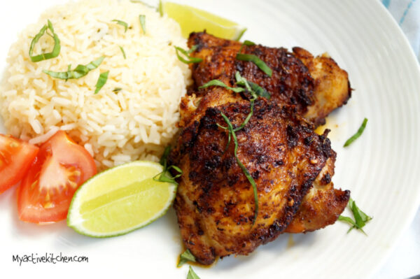 spiced chicken served with rice and a side of lime and tomatoes