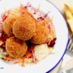 nigerian yam balls served over salad on a plate.