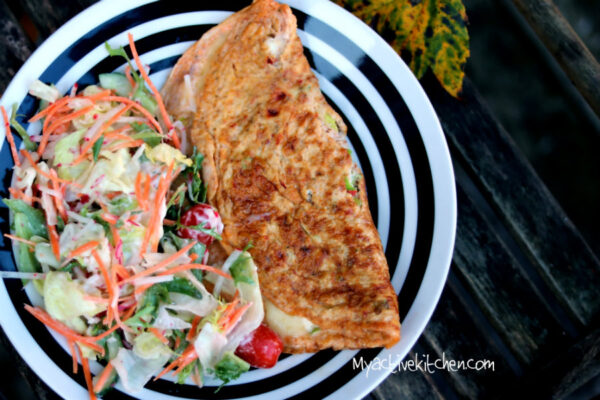 spicy omelette on a white and black plate served with salad