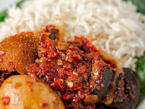 ofada stew with ponmo, assorted meat and egg soaked in stew. It is served with plain boiled rice.