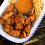 crispy fried chicken wings and chips in a pan.