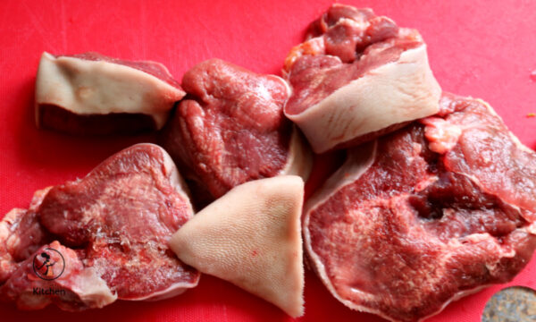 raw cow tongue steak on a red chopping board.