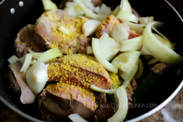 cow tongue in a pot with chopped onions and chicken bouillon.