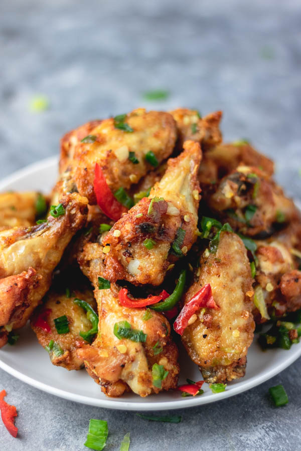 salt and pepper chicken wings on a plate placed on a blue surface.