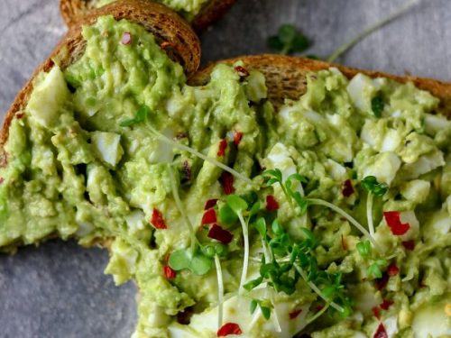 bitten slice whole meal bread with topping of salad and herbs