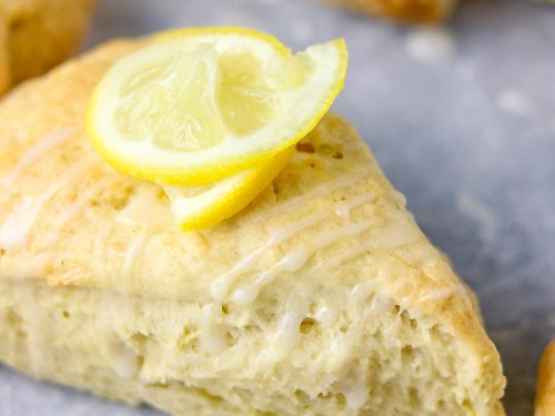 a close shot of triangular scone with a rind of lemon as garnish
