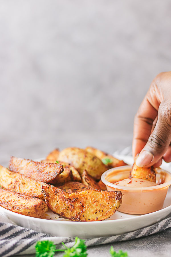 Well seasoned crispy potato wedges!! These crispy potatoes are sinfully good. Not only are they crispy on the outside, they are well seasoned and fluffy on the inside. The best part is they are baked and not fried!!! #easypotatorecipe #potatowedges #healthypotatowedges #healthyfrenchfries 