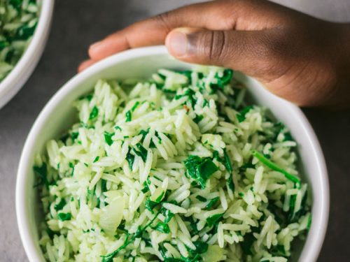 a close shot of spinach greek rice in a white bowl