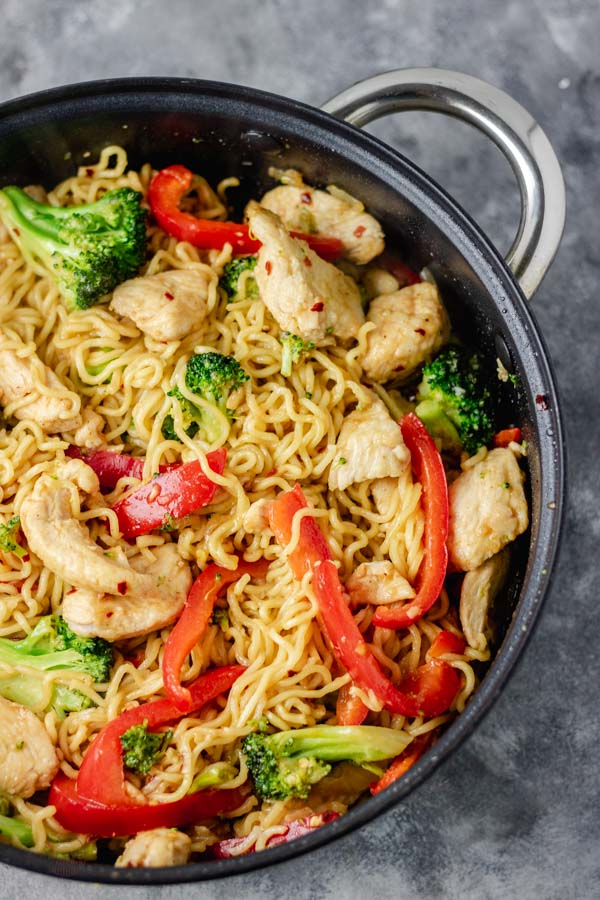 overhead cropped shot of chicken ramen noodle stir fry in a skillet made with broccoli and bell pepper and stir fry sauce.