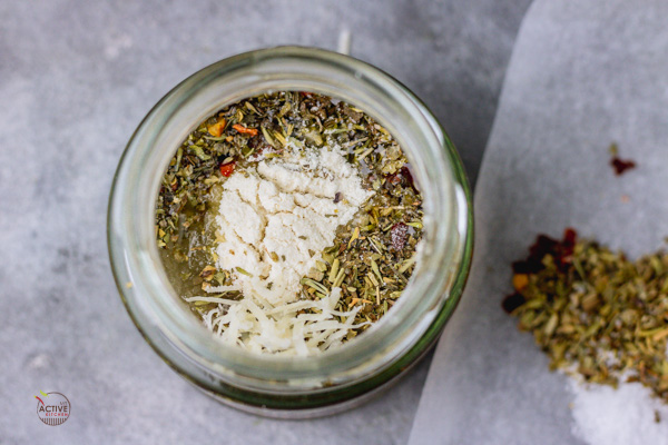 Ingredients of homemade italian dressing added to a small jar.