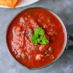 overhead shout of homemade blender salsa in a small serving saucepan and a side of corn chips.