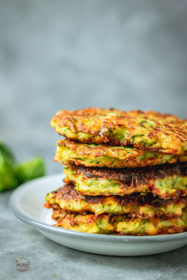 stack of crispy courgette and sweetcorn fritters on a plate.