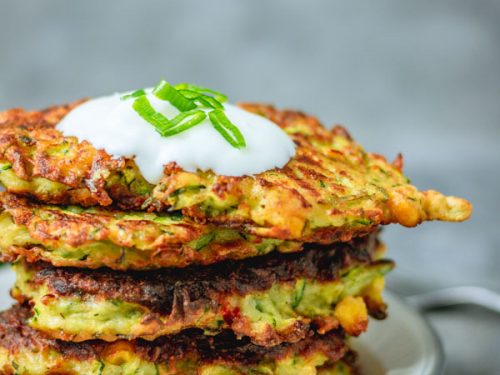 stack of crispy courgette and sweetcorn fritters on a plate.