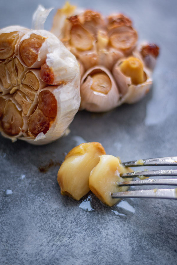 fork holding roasted garlic.