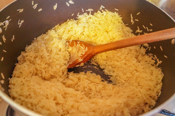 raw washed basmati rice in a pot about to be stirred.