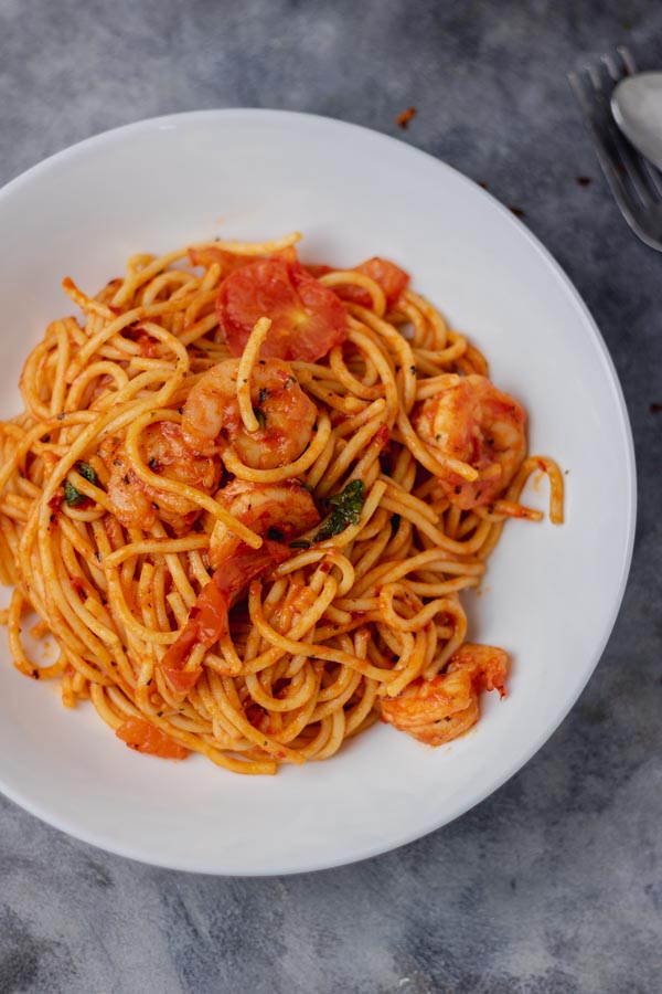 a plate of spaghetti jollof and shrimps.