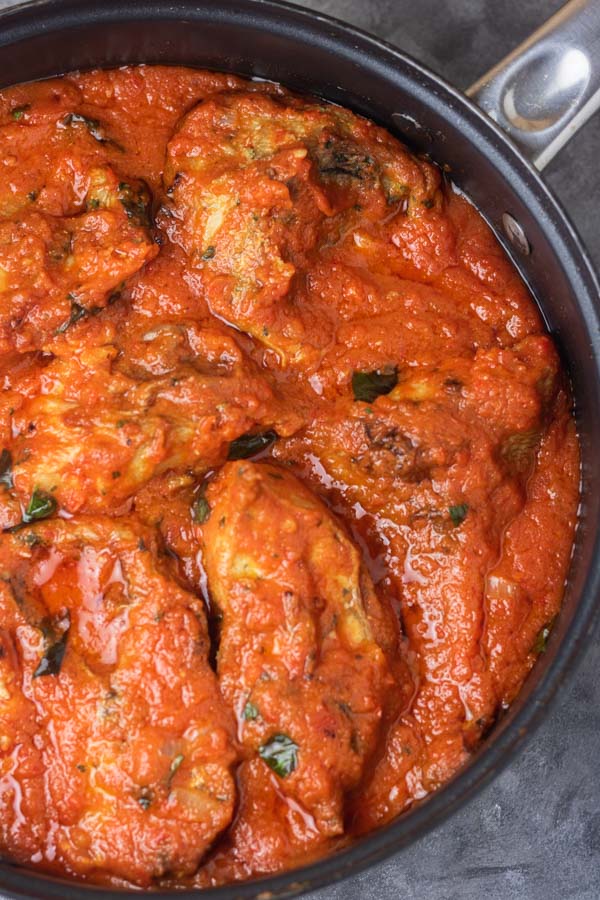 a pan of stew garnished with basil leaves.