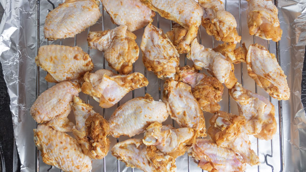marinated chicken wings arranged on a baking tray.