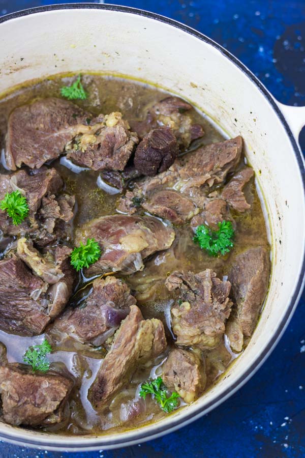 pot of cooked meat garnished with parsley.