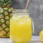 a glass of pineapple lemonade with metal straw.