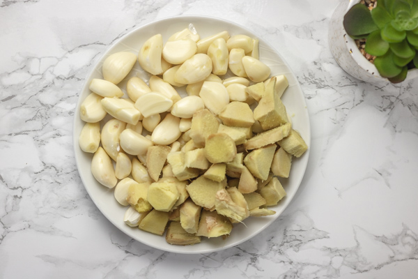 peeled garlic and ginger on a white plate.