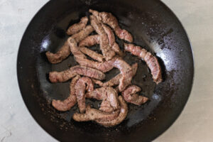 seared beef in a wok.