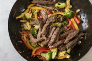 beef and vegetables in a wok.