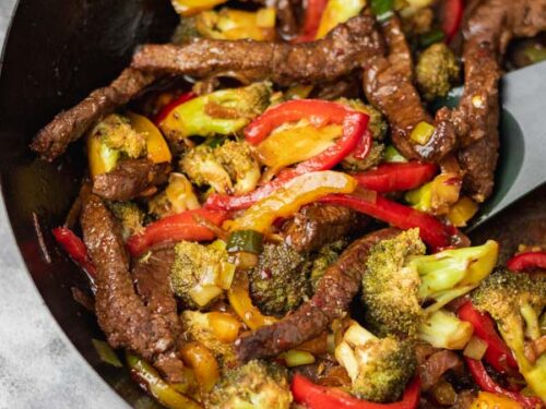 beef and broccoli stir fry in a wok.